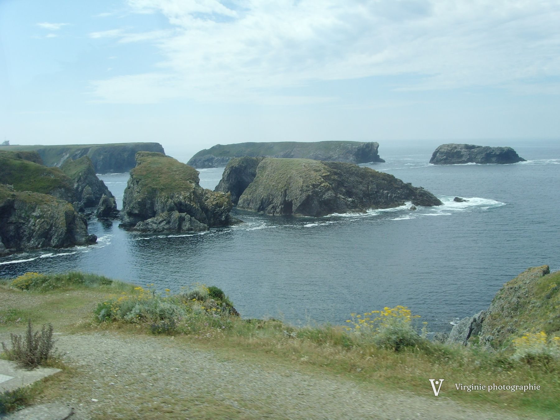 Des îlots rocheux au large d’une côte verte