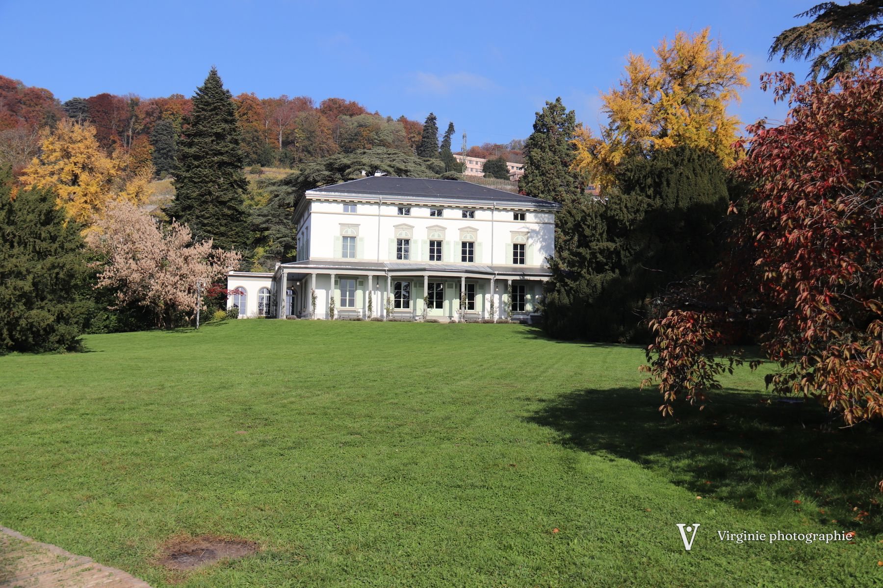 Un manoir blanc au fond d’un grand parc aux arbres d’automne