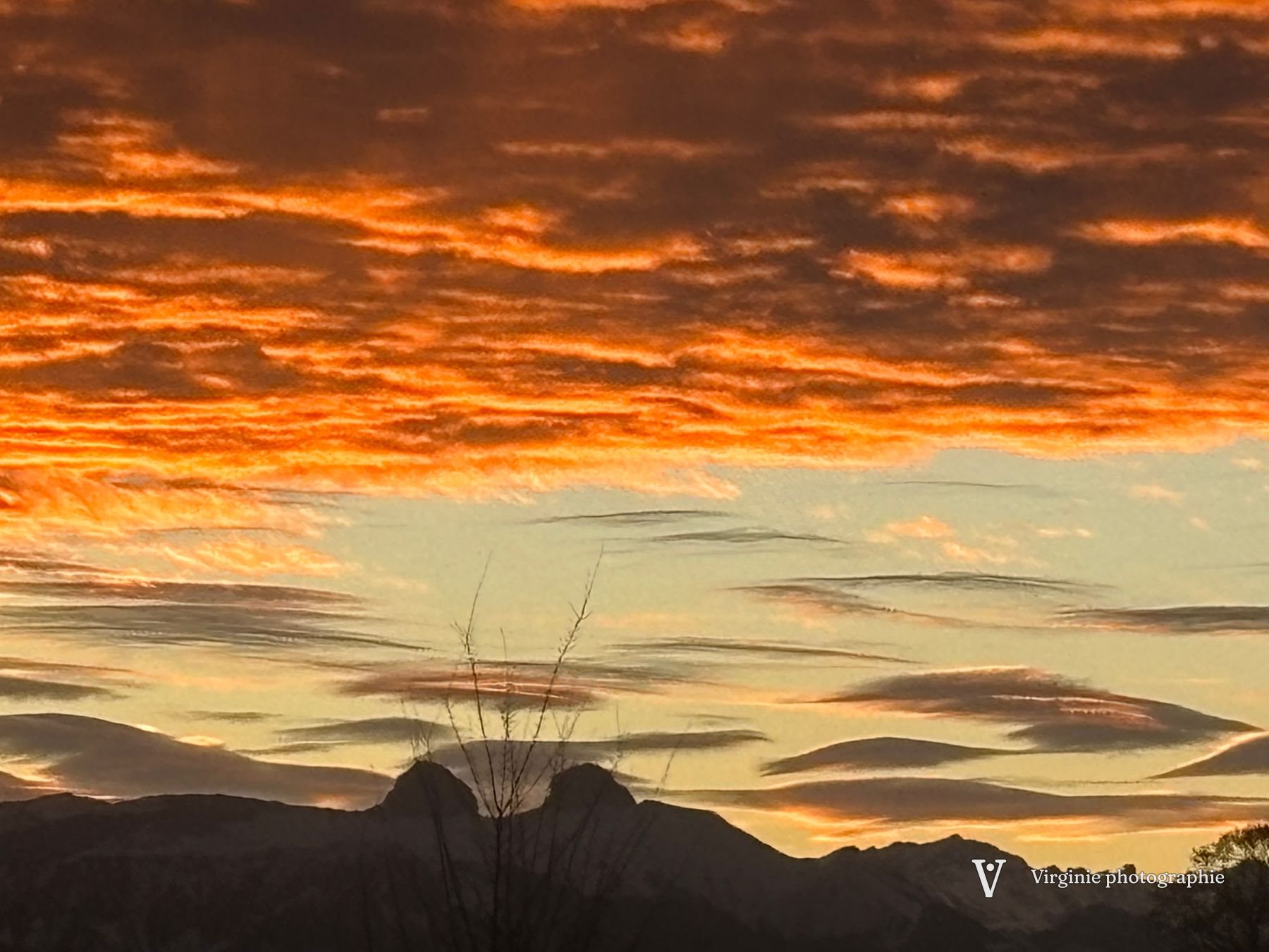 Des nuages orange et dorés au-dessus d’une silhouette de colline