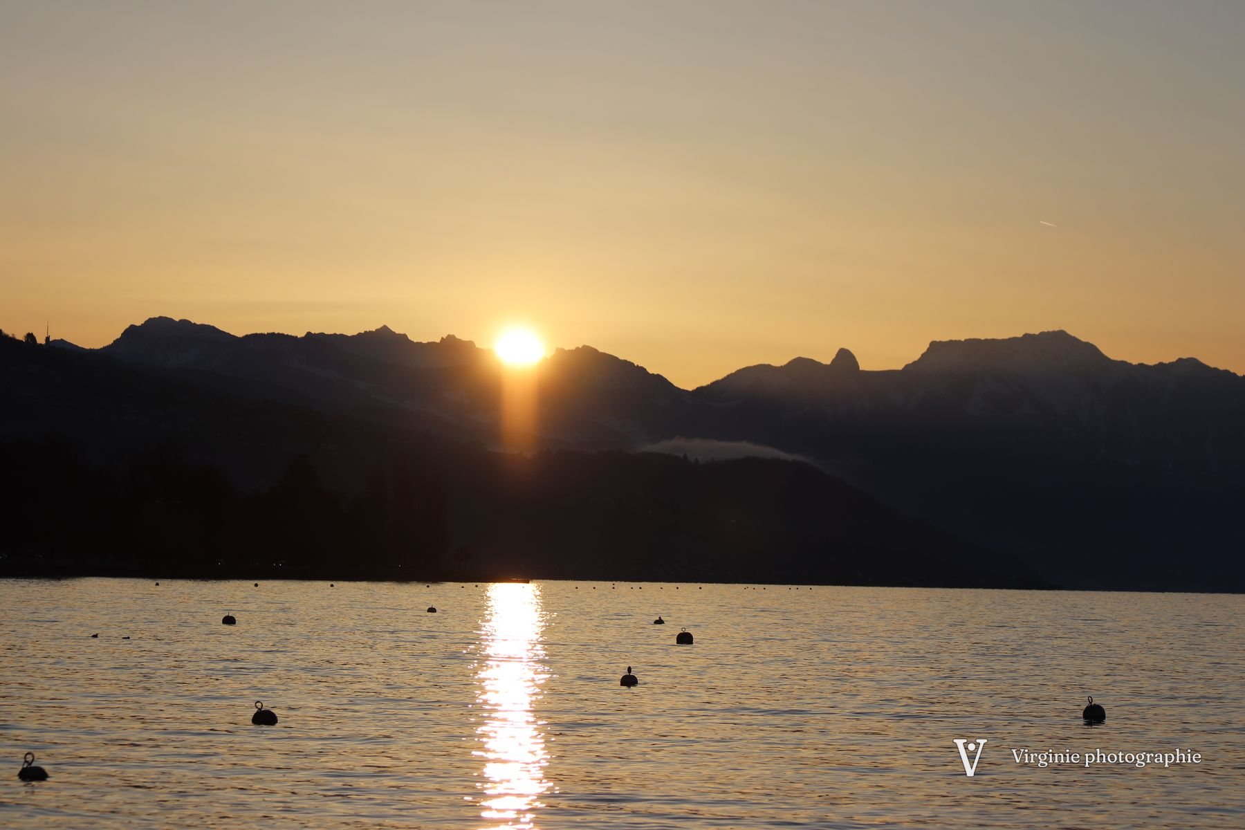 Le soleil disparaît derrière les montagnes, son reflet doré sur le lac