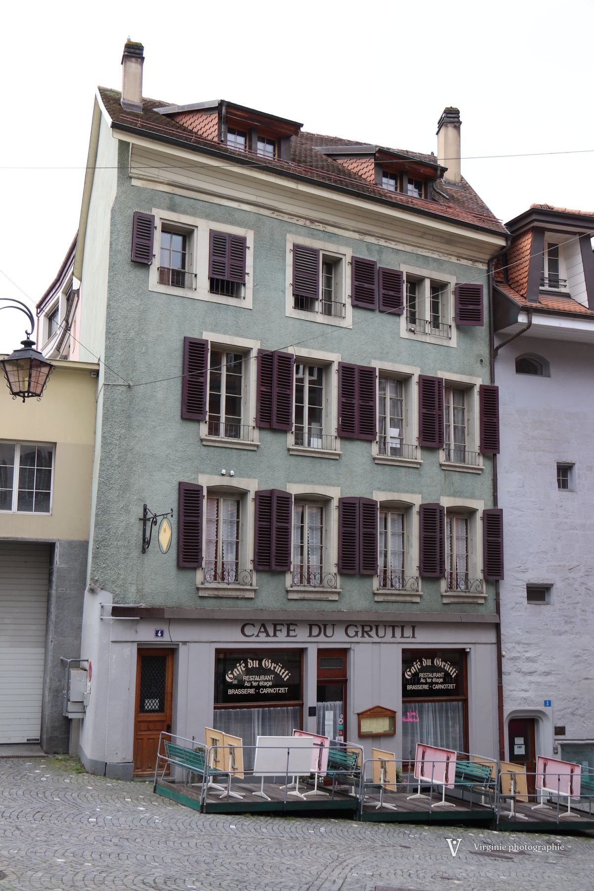 Une haute maison aux volets bordeaux, le café du Grütli au rez-de-chaussée