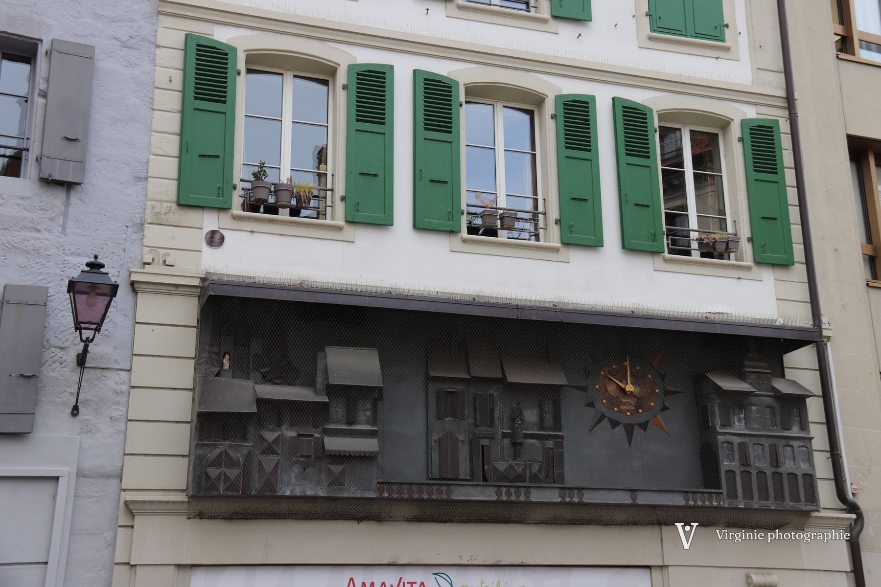 Une façade aux volets verts avec une horloge sculptée