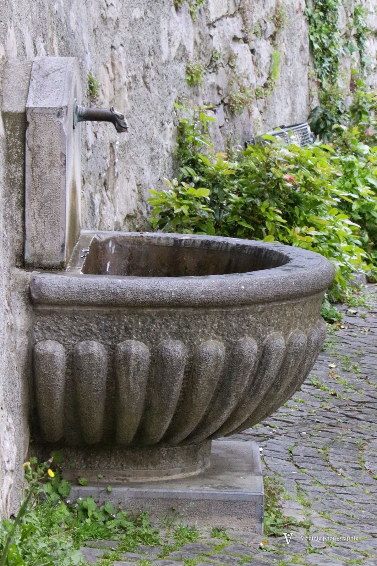 Une vasque de fontaine en pierre contre un vieux mur
