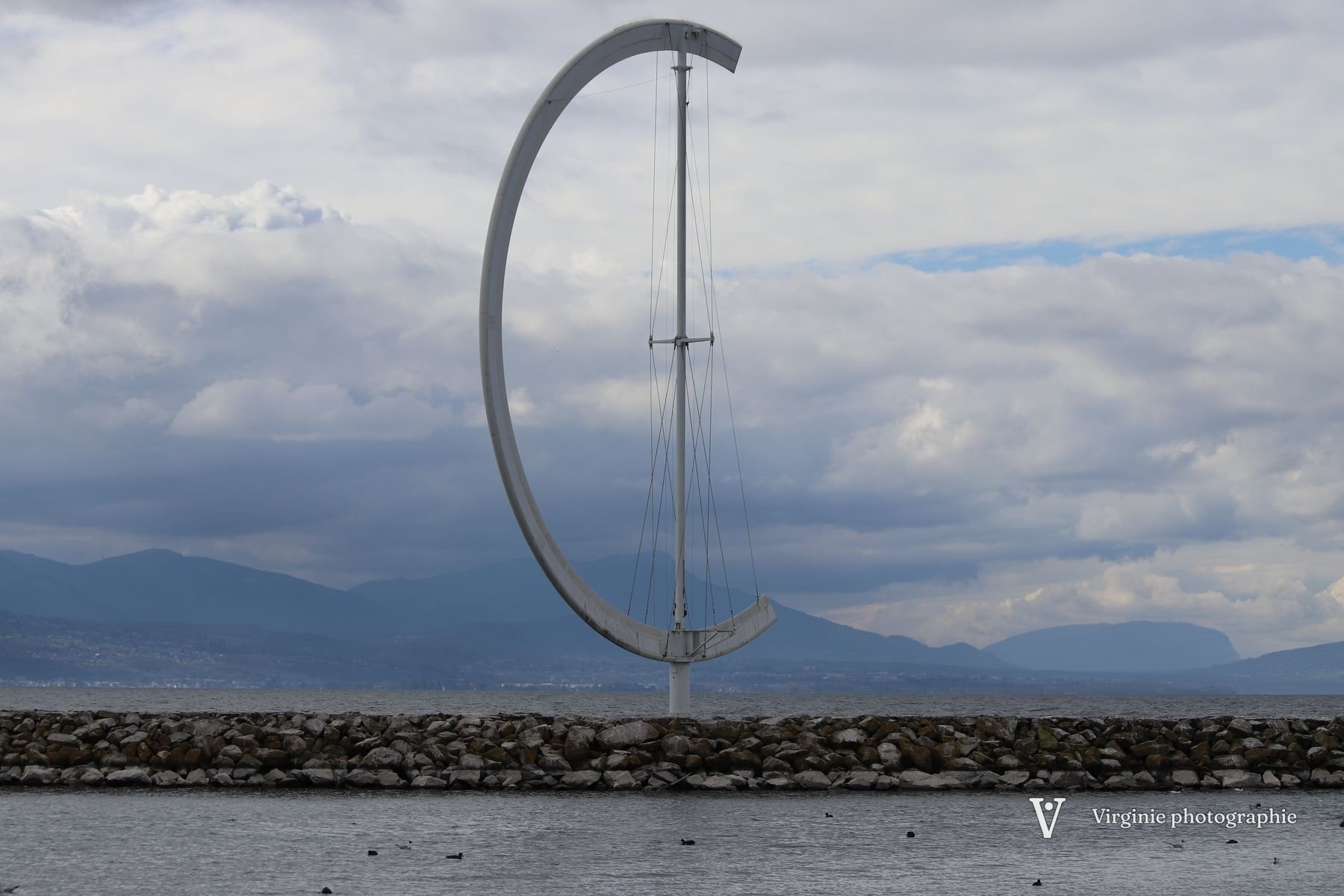 Une grande sculpture en arc de métal au bord du lac