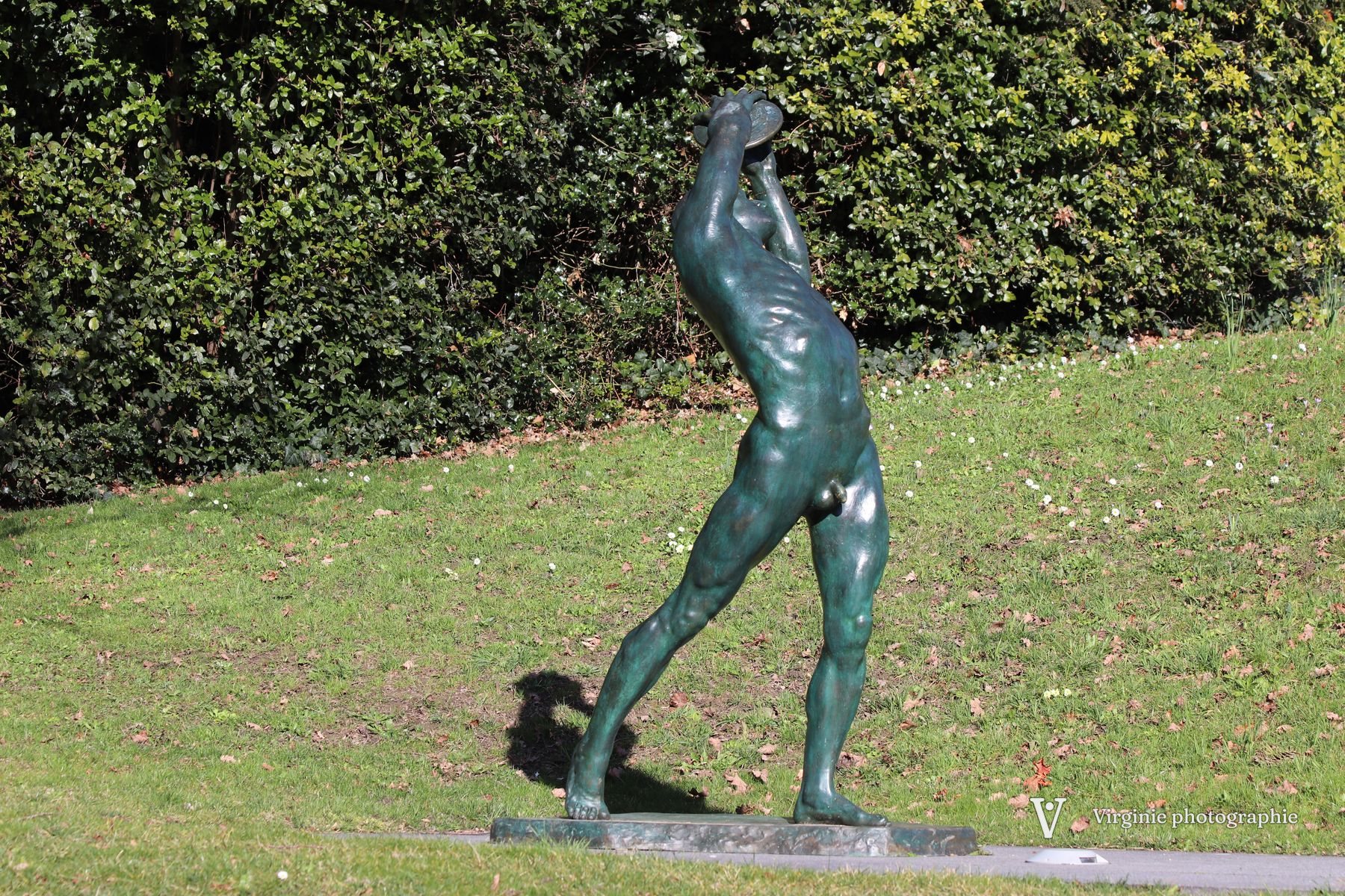 Une statue de bronze d’athlète sur une pelouse